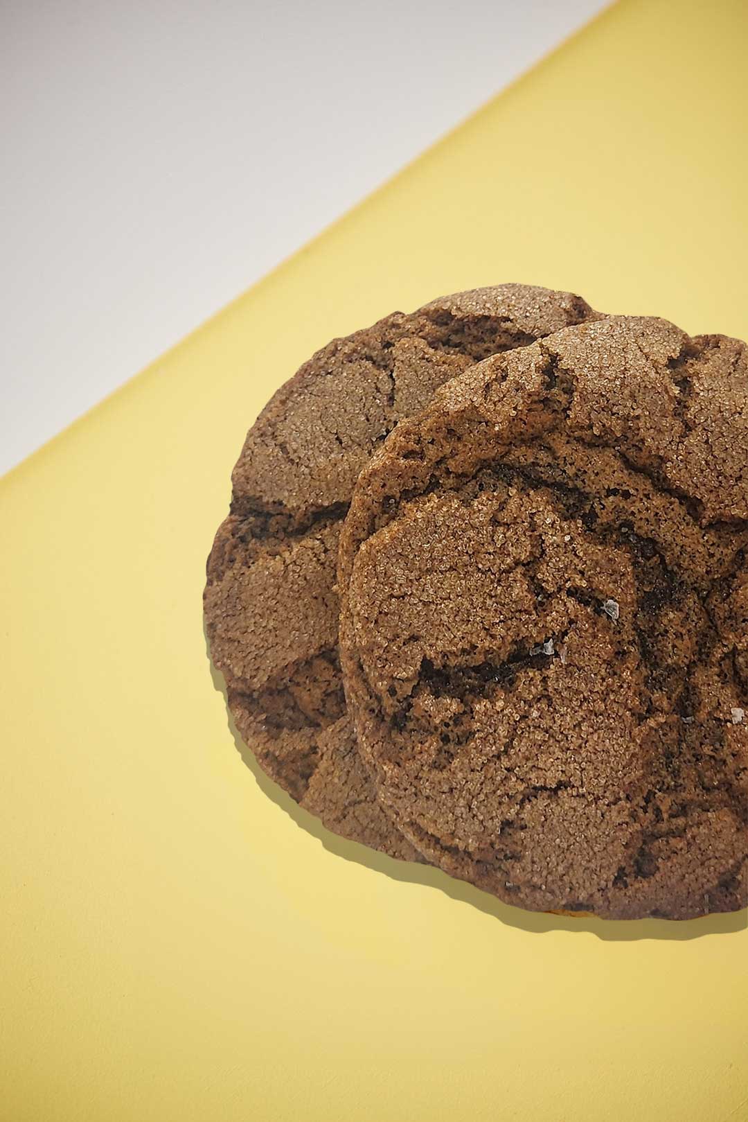 Two espresso cookies on a white and yellow background.