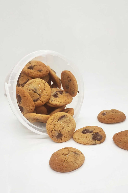 Bucket of mini chocolate chip cookies tipped over and spilling outside.