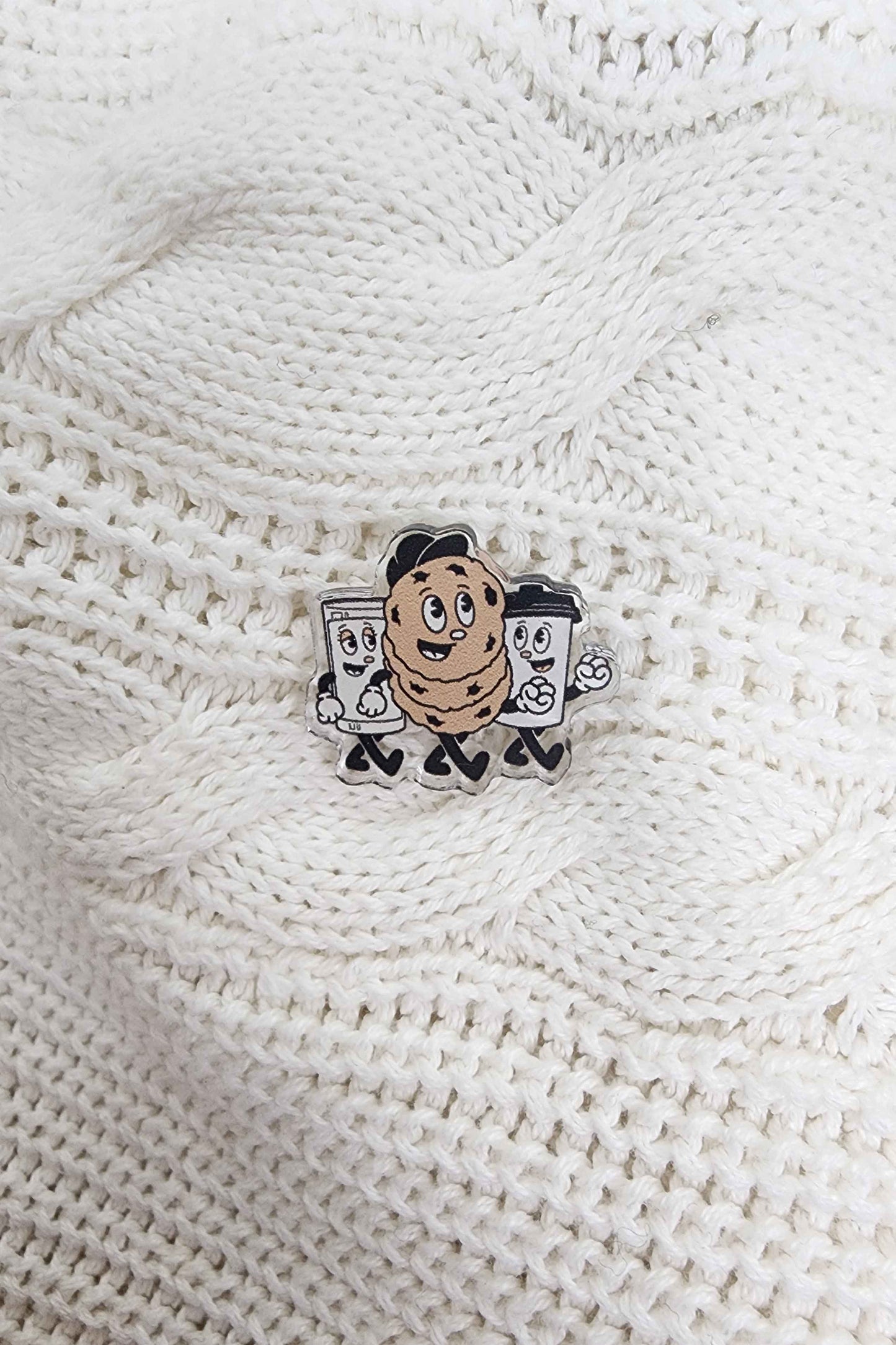 Mascot logo acrylic pin on a cable knit white sweater.